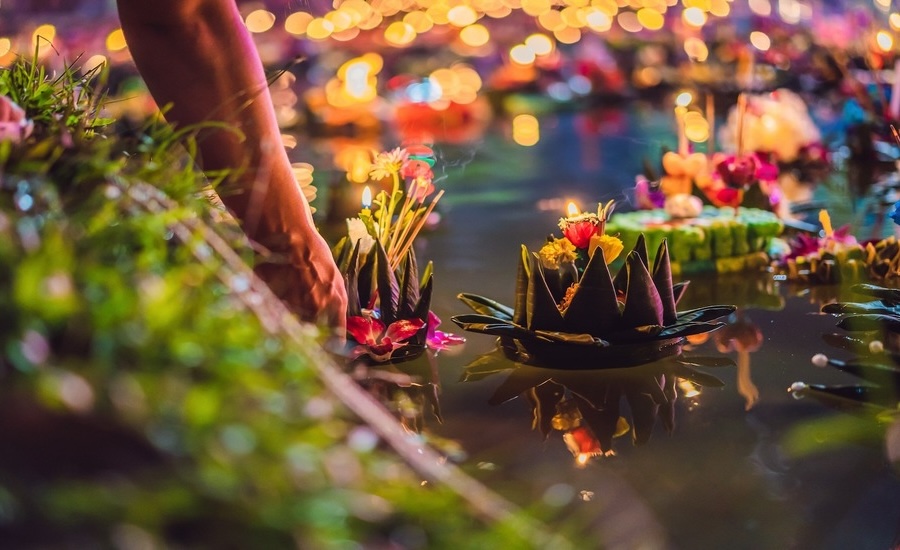 Releasing a lit flower float on water during the Loy Krathong Thai festival of light